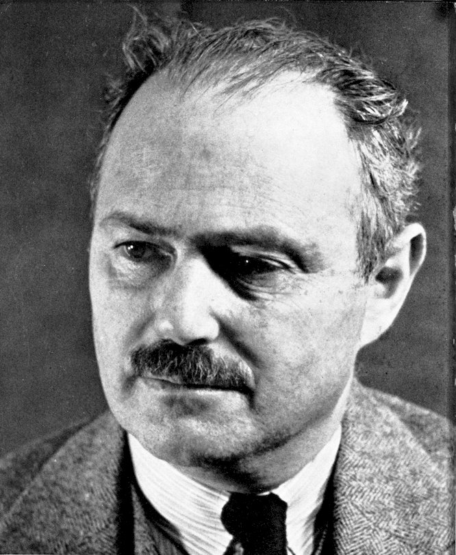 A black and white photographic portrait of a middle-aged man with a prominent mustache, thinning hair, and a thoughtful expression, looking slightly downward.